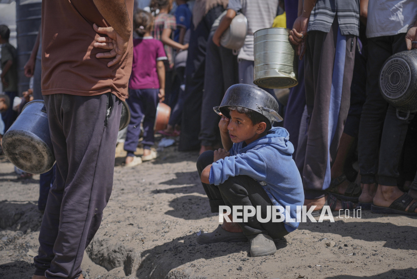 Seorang anak laki-laki memegang panci kosong saat menunggu bantuan makanan dari dapur umum di Khan Younis, Jalur Gaza, Jumat (9/5/2025).
