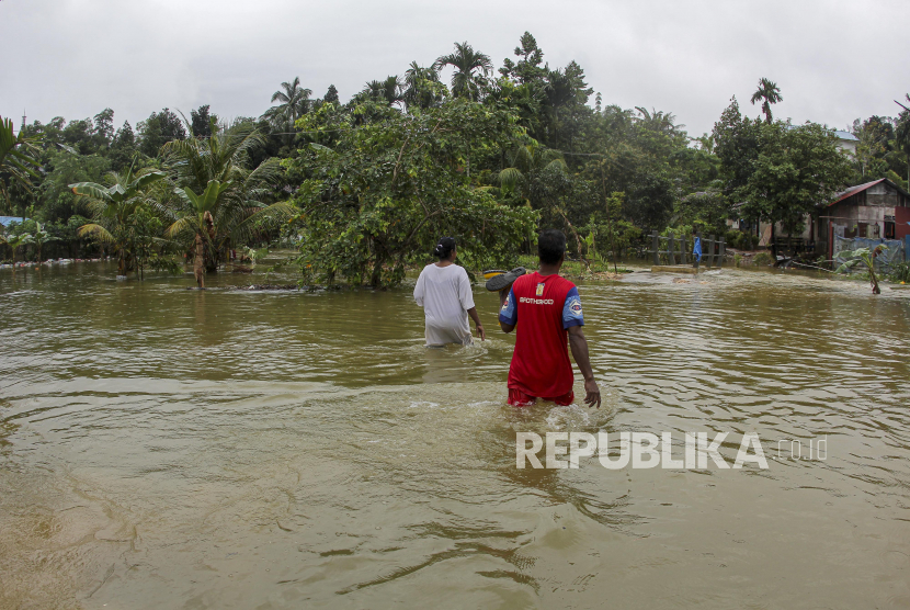 Warga berjalan menembus banjir yang merendam  salah satu kawasan permukiman di daerah Muka Kuning, Batam, Kepulauan Riau, Ahad (2/1/2022). BPBD memetakan daerah rawan banjir dan longsor di Riau.