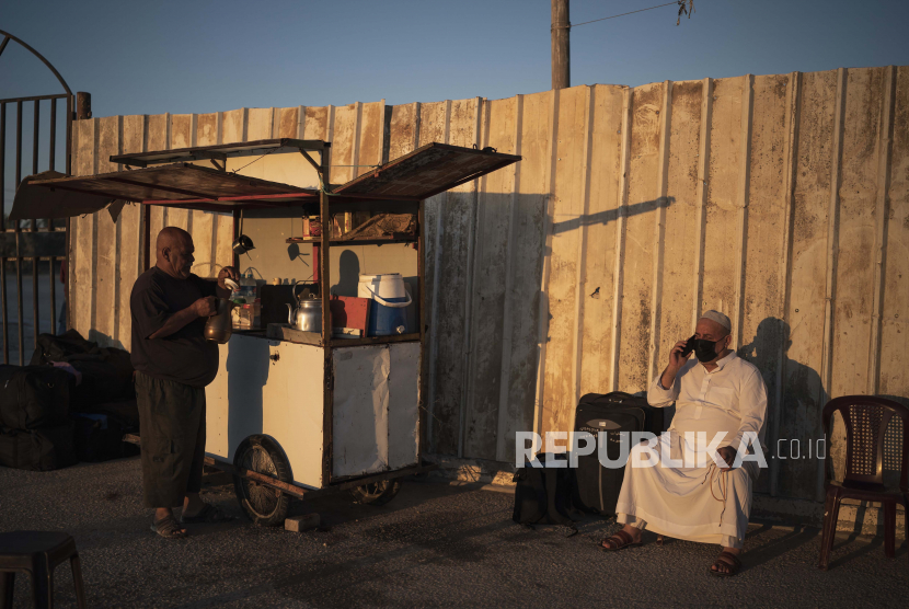 Seorang pedagang menyiapkan teh saat seorang pria Palestina duduk di samping kopernya sebelum melintasi perbatasan Rafah dengan Mesir, Jalur Gaza selatan, Minggu, 6 Juni 2021.