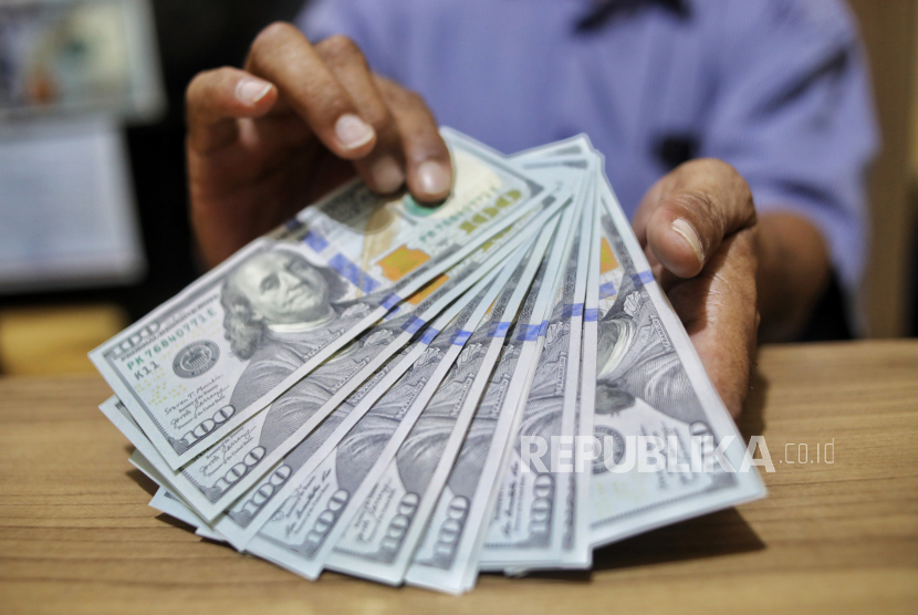 Petugas menunjukan uang dollar AS di Money Changer, Jakarta, Rabu (17/4/2024).