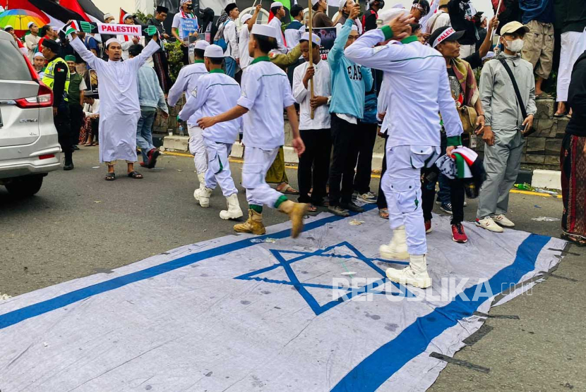 Massa aksi Bogor Raya Bela Palestina  menginjak-injak dan membakar bendera Israel pada Rabu (25/10/2023) di Tugu Kujang, Kota Bogor. 