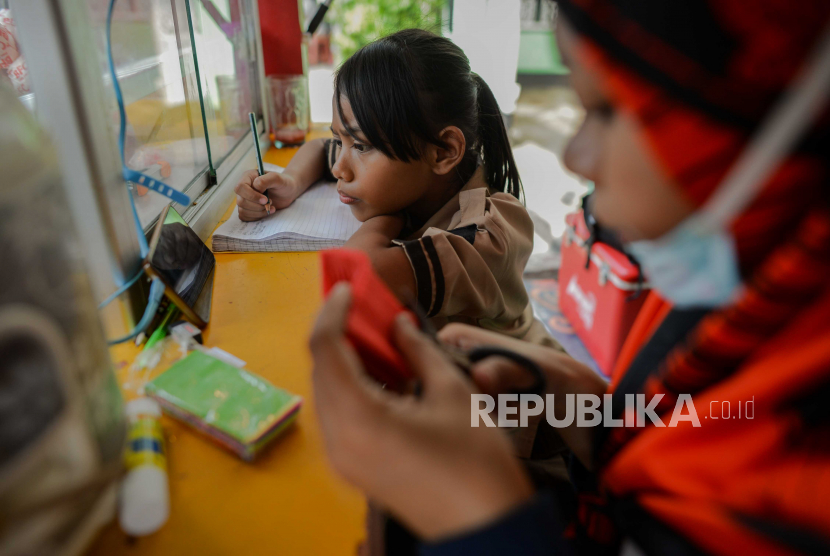 Siswi kelas 2 SDN 01 Pagi Bukit Duri Keysha belajar daring ditemani ibunya Okta (31) di gerai makanan tempat Ibunya kerja di kawasan Bukit Duri, Jakarta, Rabu (29/7). Pembelajaran Jarak Jauh (PJJ) dengan menggunakan metode daring dan bimbingan orang tua masih menjadi kendala, menurut Okta selain harus mencari nafkah untuk keluarganya Ia harus tetap membimbing anaknya belajar di tempatnya bekerja.