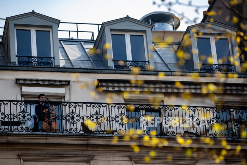 Seorang musisi memainkan cello di balkon rumahnya di pusat kota Paris, Prancis, Sabtu (28/3). Prancis menerapkan kebijakan Lockdown sebagai upaya untuk menghentikan penyebaran virus corona