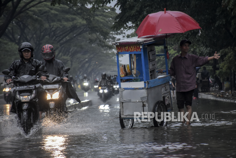 Warga melintasi genangan banjir di kawasan Gedebage, Bandung, Jawa Barat, Jumat (1/12/2023). Kawasan tersebut kerap dilanda banjir akibat drainase yang buruk saat intensitas curah hujan yang tinggi. Genangan banjir tersebut mengganggu akses lalu lintas dan merendam sebagian kawasan Pasar Gedebage.