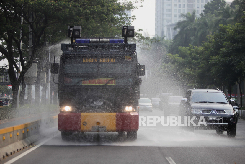 Mobil kepolisian menyemprotkan air di Jalan Jenderal Sudirman, Jakarta, Rabu (23/8/2023). Penyemprotan di sekitar jalan protokol tersebut sebagai upaya untuk membersihkan debu-debu yang bertebaran di jalanan akibat polusi udara.