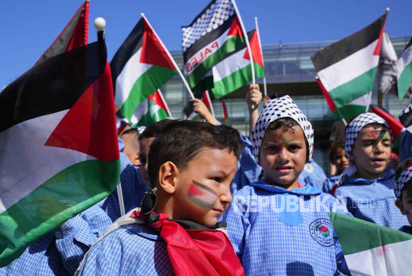 Anak-anak Palestina yang tinggal di Lebanon mengibarkan bendera nasional mereka saat protes solidaritas terhadap rakyat Palestina di Gaza, di depan Markas Besar PBB di Beirut, Lebanon, Kamis, 26 Oktob