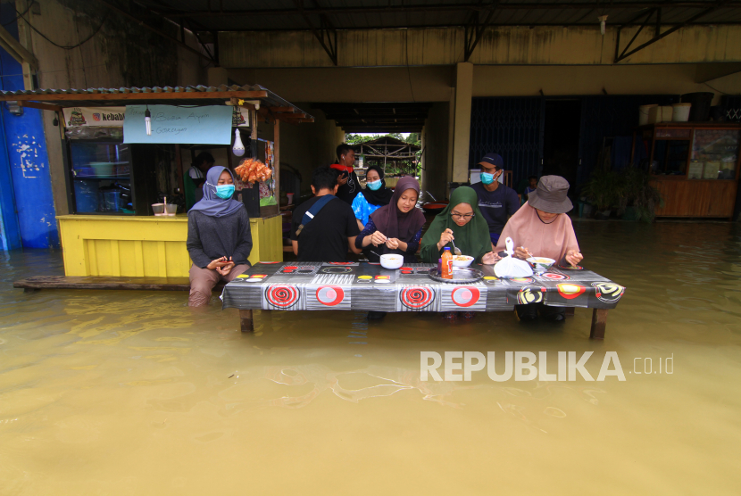 Sejumlah warga menyantap makanan di sebuah warung yang terendam banjir di Putussibau, Kabupaten Kapuas Hulu, Kalimantan Barat, Selasa (15/9/2020). Banjir setinggi 1-5 meter yang melanda Putussibau sejak Minggu (13/9/2020) hingga Selasa (15/9/2020) melumpuhkan aktivitas masyarakat di kota tersebut. 