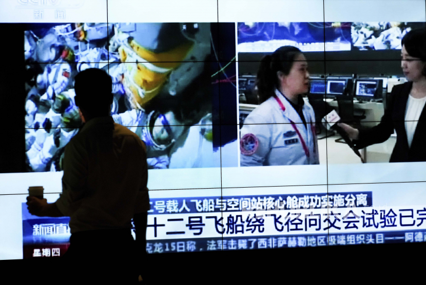  Seorang pria dalam siluet ketika dia menonton layar TV yang menunjukkan CCTV yang menyiarkan berita tentang astronot China yang duduk di dalam pesawat ruang angkasa berawak Shenzhou-12 yang bersiap untuk kembali ke bumi, di sebuah pusat perbelanjaan di Beijing, Kamis, 16 September 2021.
