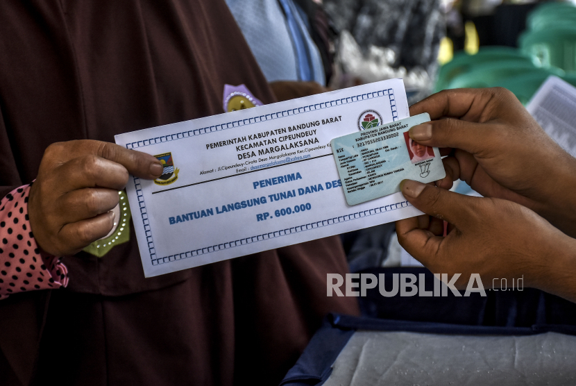 Panitia memberikan Bantuan Langsung Tunai Dana Desa kepada warga di Lapangan Desa Margalaksana, Cipendeuy, Kabupaten Bandung Barat, Jumat (29/5). Kemendes PDTT mencatat ada 23 kabupaten yang penyaluran BLT Dana Desa masih nol persen.