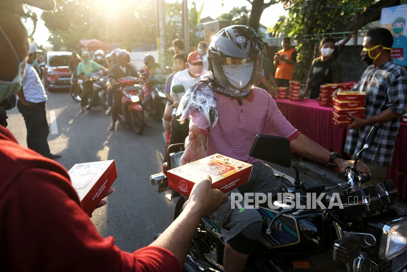 Petugas membagikan makanan untuk berbuka puasa (takjil) kepada warga di kawasan Masjid Jogokariyan, Yogyakarta, Jumat (24/4/2020). Akibat pandemi COVID-19, tradisi takjil 