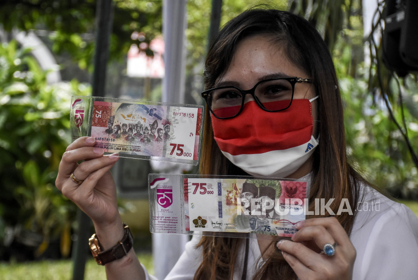 Warga menunjukkan uang baru pecahan Rp 75 ribu yang telah ditukarnya. 