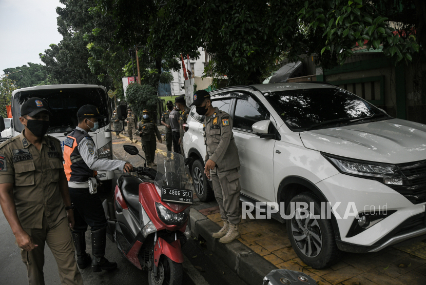 Sejumlah petugas gabungan dari Dinas Perhubungan dan Satpol PP menertibkan mobil dan motor yang parkir liar di trotoar kawasan Duren Sawit, Jakarta Timur, Kamis (9/6/2022).  Pada penertiban tersebut para pemilik kendaraan yang melanggar diberikan teguran dan surat peringatan agar tidak mengulangi perbuataannya. 