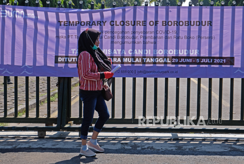 Warga berjalan melintasi spanduk pengumuman di gerbang masuk kawasan Taman Wisata Candi (TWC) Borobudur, Magelang, Jawa Tengah, Selasa (29/6/2021). PT Taman Wisata Candi Borobudur, Prambanan, dan Ratu Boko (PT TWC-Persero) kembali melakukan penutupan sementara operasional Taman Wisata Candi Borobudu mulai tanggal 29 Juni guna mendukung pelaksanaan PPKM Mikro dalam rangka mencegah penyebaran Covid-19 di wilayah Kabupaten Magelang. 