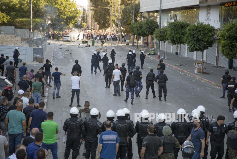 Polisi anti huru hara Palestina dan petugas keamanan berpakaian preman bentrok dengan demonstran menyusul unjuk rasa memprotes kematian kritikus vokal Otoritas Palestina Nizar Banat, di kota Ramallah, Tepi Barat, Sabtu, 26 Juni 2021. 