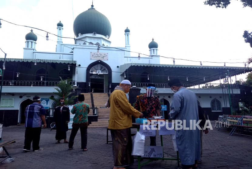 Petugas membagikan kartu pembagian tempat shalat Jumat berjamaah di Masjid Syuhada, Yogyakarta, Jumat (12/6). Shalat Jumat ini yang pertama usai penutupan masjid imbas pandemi virus corona