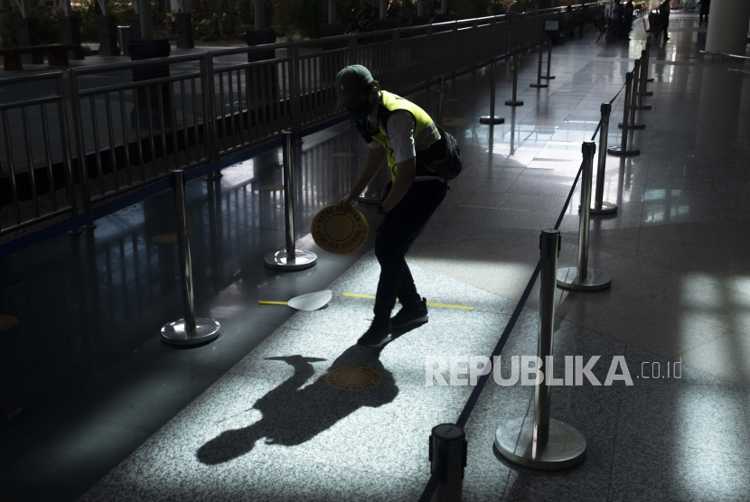  Seorang pekerja menempelkan tanda jarak fisik di area kedatangan internasional selama pembukaan bandara Internasional Ngurah Rai di Bali, Indonesia, 14 Oktober 2021. 