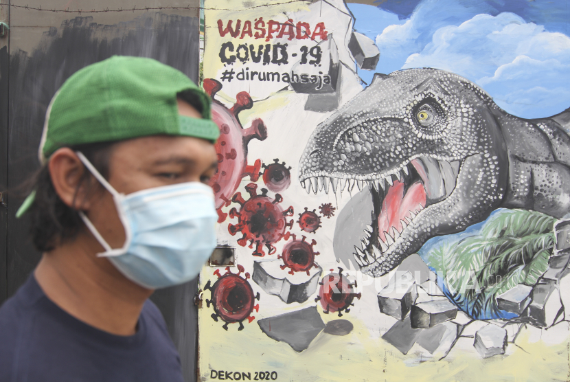 Seorang warga melintas di depan mural bertema COVID-19 di Jalan Baru, Depok, Jawa Barat, Senin (30/3/2020). Mural karya Komunitas Mural Depok tersebut merupakan media edukasi kepada warga agar waspada potensi penyebaran virus corona atau COVID-19