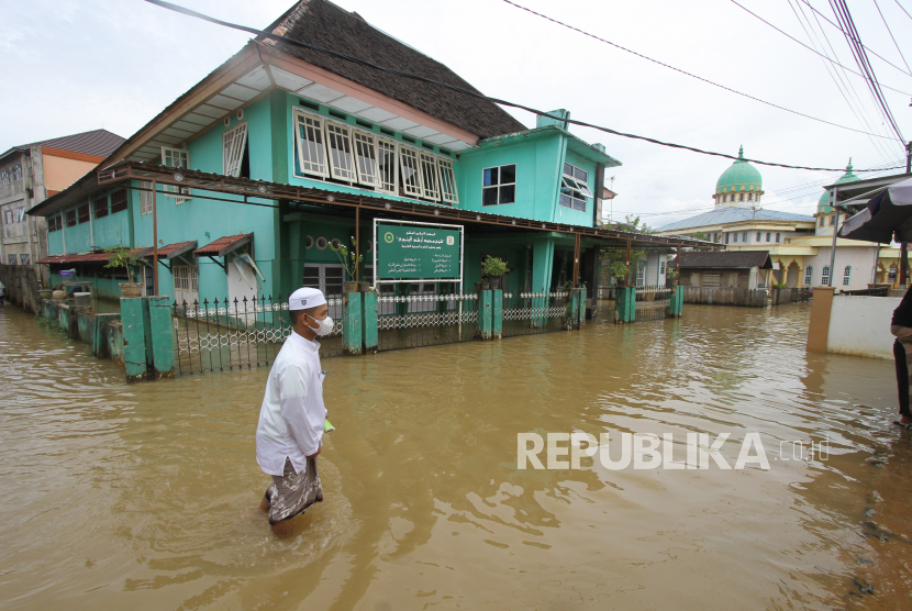 Warga melintasi jalan yang tergenang banjir di Desa Dalam Pagar Ulu, Kabupaten Banjar, Kalimantan Selatan, Senin (27/2/2023). Badan Nasional Penanggulangan Bencana (BNPB) mencatat frekuensi kejadian bencana mingguan pekan ketiga Maret mulai menurun.