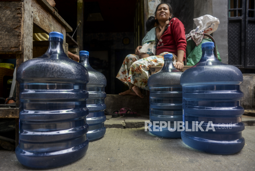 Warga duduk di dekat pengisian air bersih dalam galon di Gang Madrasah, Ancol, Kecamatan Pademangan, Jakarta Utara, Rabu (5/1).