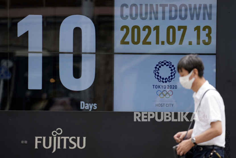  Seorang pria yang mengenakan masker wajah melawan penyebaran virus corona berjalan di depan kalender hitung mundur yang menunjukkan 10 hari untuk memulai Olimpiade Tokyo 2020 Selasa, 13 Juli 2021, di Tokyo.