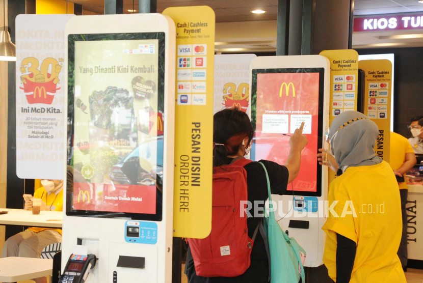 Pengunjung sedang melakukan transaksi pembayaran dengan scan kode QRIS di salah satu gerai McDonald