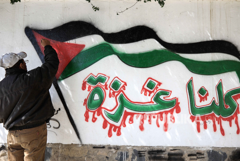 Seorang seniman Yaman melukis grafiti bendera Palestina dalam bahasa Arab Kita semua Gaza dalam solidaritas dengan rakyat Palestina, di Sanaa, Yaman, 02 November 2023. 