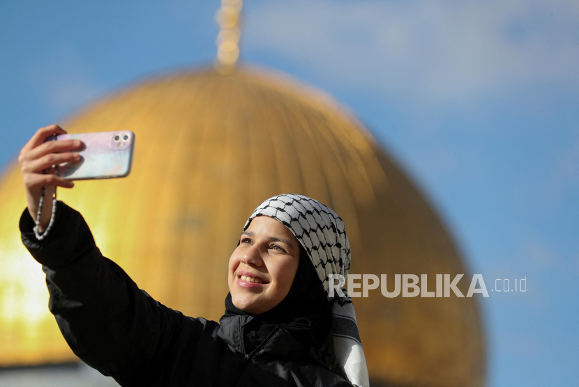 Seorang warga Palestina melakukan swafoto saat menghadiri perayaan hari raya Idul Fitri di Masjid Al-Aqsa di Kota Tua Yerusalem, Jumat, (21/4/2023). Otoritas Israel mencegah azan magrib dikumandangkan di Masjid Al Aqsa pada Senin (24/4/2023).