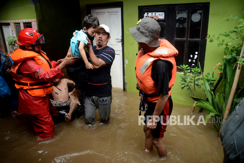 Petugas membantu warga melintasi banjir yang merendam kawasan Kebon Pala, Kampung Melayu, Jatinegara. BPBD sebut sebanyak 69 RT di DKI Jakarta terendam banjir.