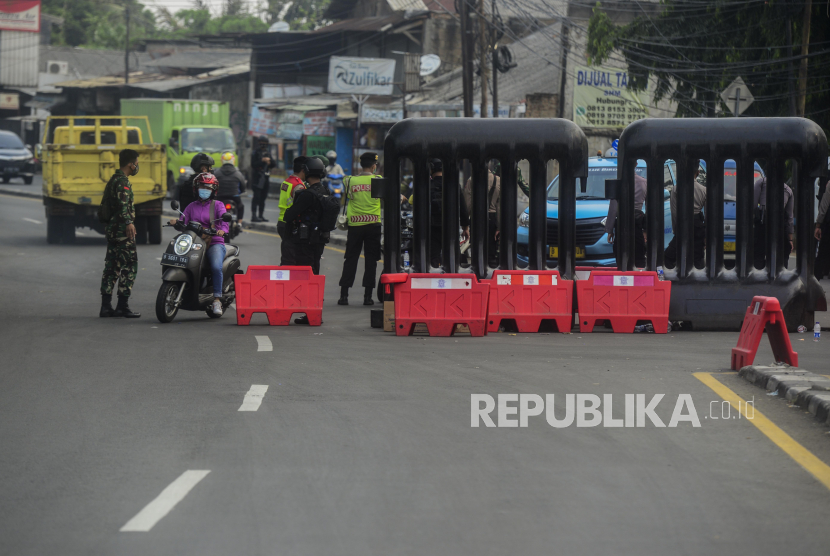 Sejumlah petugas gabungan berjaga saat melakukan penyekatan di Jalan Raya Bogor-Jakarta, Depok, Jawa Barat, Selasa (6/7). Kepadatan arus lalu lintas kendaraan di Pos penyekatan Pemberlakuan Pembatasan Kegiatan Masyarakat (PPKM) Darurat tersebut sudah berkurang hingga 70 persen pada hari ini. Republika/Putra M. Akbar