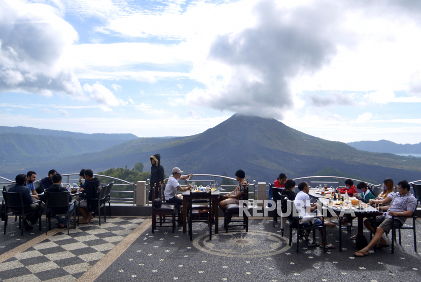 Wisatawan menikmati pemandangan alam Gunung Batur dari sebuah restoran di kawasan Kintamani, Bangli, Bali.
