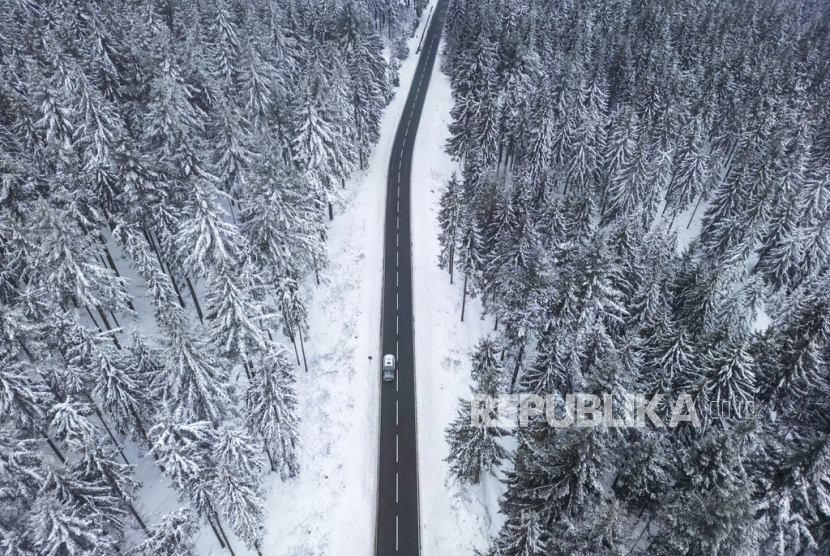 Sebuah mobil melaju di sepanjang pepohonan yang tertutup salju (ilustrasi).
