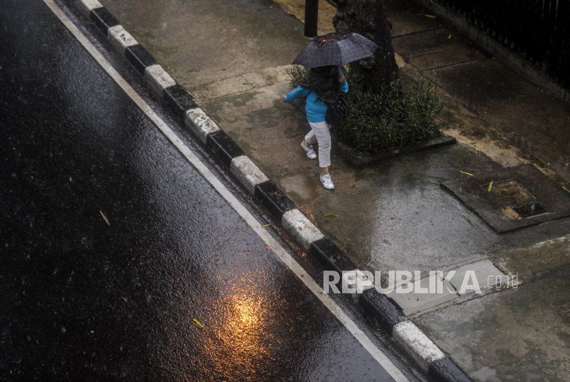 Warga berjalan memakai payung saat hujan di kawasan Kuningan, Jakarta (ilustrasi). Kementerian LHK menyiapkan peringatan dini dampak La Nina.
