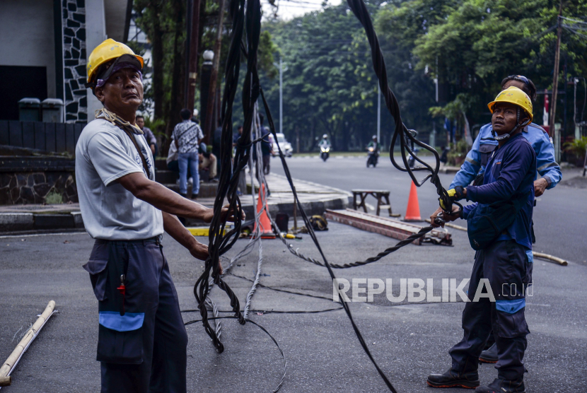 Petugas PLN memperbaiki jaringan kabel listrik yang menjuntai ke jalan di Jalan Pemuda, Kota Bogor, Jawa Barat, Jumat (27/1/2023). PT Perusahaan Listrik Negara (PLN) pada tahun sejak tahun 2020 hingga tahun 2022 membayar utang obligasi sebesar Rp 62,5 triliun.