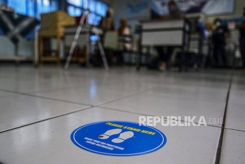 Stiker jaga jarak yang terpasang di lantai saat simulasi sekolah di SMP. Ilustrasi