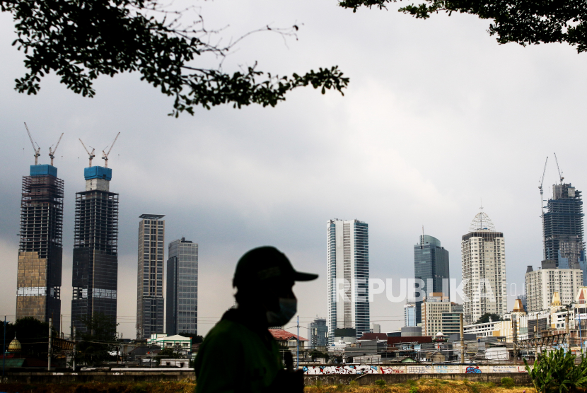 Warga melintas dengan latar belakang gedung bertingkat di Jakarta, Rabu (21/7). Pemerintah menyebut secara kumulatif jumlah kasus Covid-19 di Indonesia sejak 2020 masih di bawah sejumlah negara seperti Amerika Serikat, India, dan Brasil.