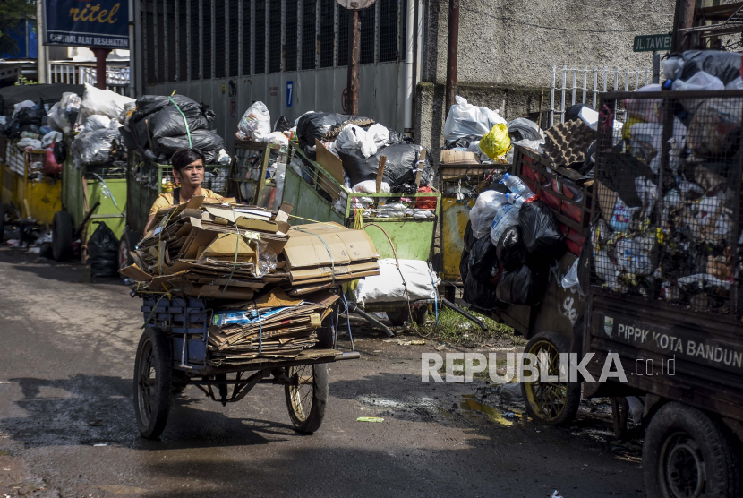 Warga melintas di samping tumpukan sampah di kawasan Pungkur, Kecamatan Regol, Kota Bandung. Sebanyak 60 ton sampah diangkut saat puncak malam tahun baru di Bandung, Jabar.