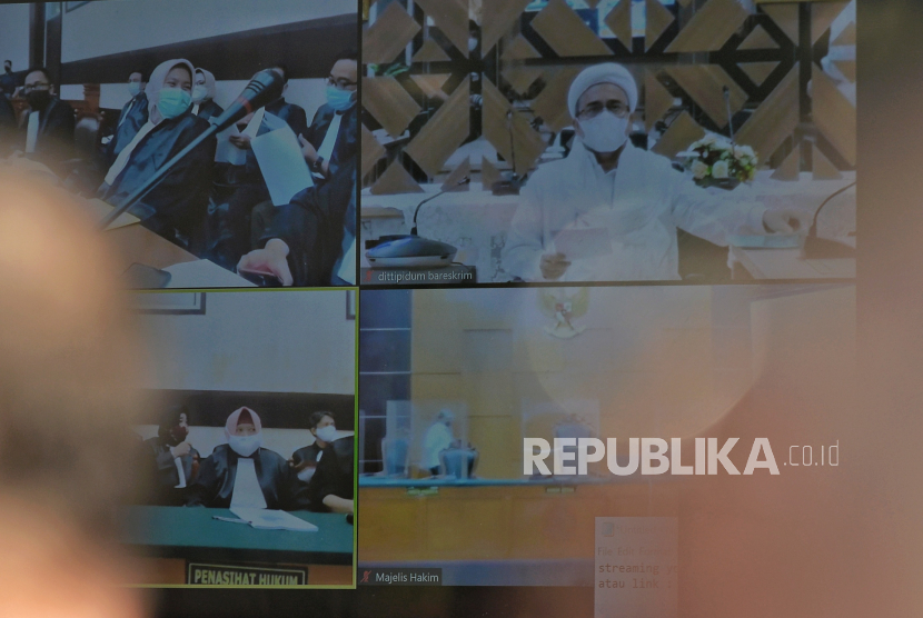 Layar yang menampilkan suasana sidang perdana atas kasus pelanggaran protokol kesehatan dengan terdakwa mantan Pemimpin Front Pembela Islam Rizieq Shihab yang digelar secara virtual di Pengadilan Negeri Jakarta Timur, Selasa (16/3). 