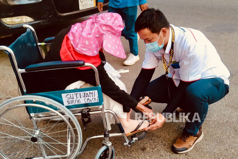 Petugas Haji Layanan Lansia sedang membantu jamaah haji lansia yang menggunakan kursi roda. 