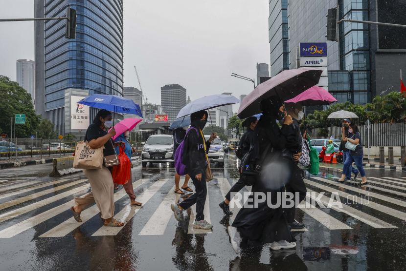 Orang-orang memegang payung di bawah hujan. Anggota Komisi VII DPR Mulyanto menyayangkan sikap Badan Riset dan Inovasi Nasional (BRIN) ketika menyampaikan prakiraan cuaca pada 28 Desember 2022. 