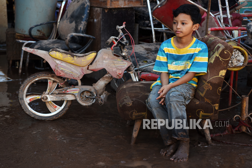 Seorang anak duduk di dekat sepedanya yang diterjang akibat banjir bandang di Pasar Sentral Bantaeng, Sulawesi Selatan.