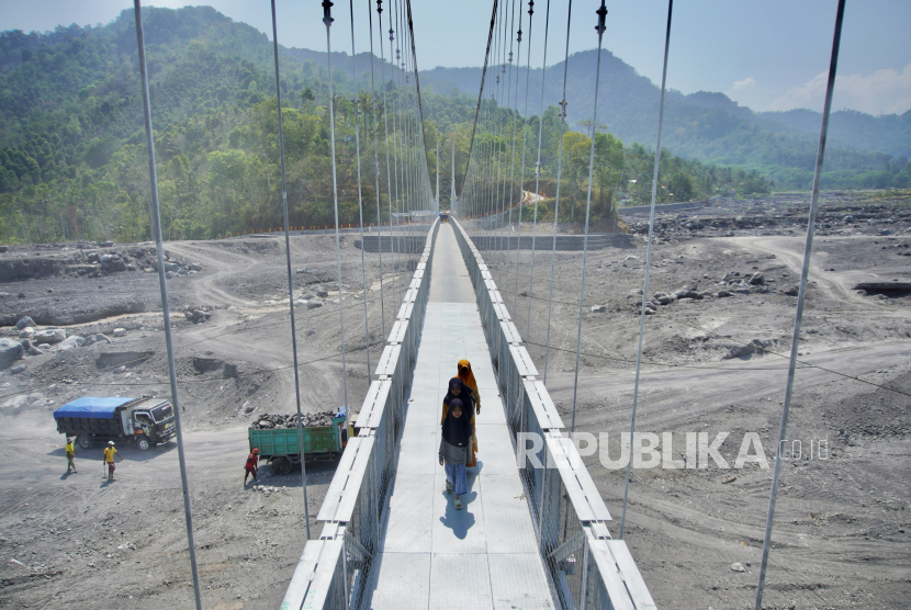 Warga melintas di atas Jembatan Gantung Kaliregoyo, Lumajang, Jawa Timur, Kamis (26/10/2023). Jembatan penghubung antardusun yang sempat tidak dapat dilintasi karena putus akibat diterjang banjir lahar hujan Gunung Semeru pada (7/7) tersebut telah diperbaiki dengan total anggaran Rp7 miliar sehingga telah berfungsi kembali.  
