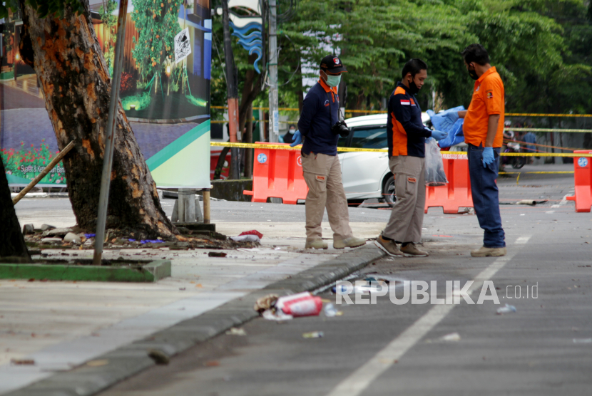 Anggota polisi mengumpulkan sisa serpihan ledakan bom bunuh diri di depan Gereja Katedral Makassar, Sulawesi Selatan, Senin (29/3/2021). Kepolisian masih melakukan olah TKP serta mengumpulkan serpihan sisa ledakan pada hari kedua pascaledakan bom bunuh diri yang terjadi pada Minggu (28/3/2021) di depan gereja tersebut. 