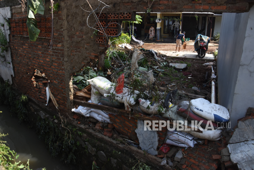 Warga membersihkan rumahnya pascabanjir yang merobohkan tembok pembatas kali di perumahan Green Malaka Residence, Ciracas, Jakarta, Ahad (11/10/2020). Banjir yang merendam sejumlah permukiman di Ciracas itu disebabkan karena meluapnya Kali Cipinang akibat hujan lebat pada Sabtu (10/10) kemarin. 