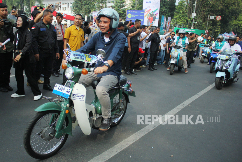 Pj Gubernur Jawa Barat (Jabar) Bey Machmudin mencoba sepeda motor yang sudah dimodifikasi menjadi tenaga listrik saat pembukaan West Java Festival (WJF) 2024, di kawasan Gedung Sate, Kota Bandung, Jumat (23/8/2024). Event WJF yang bertajuk Harmoni Kolaborasi ini diselenggarakan dalam rangka Hari Jadi Provinsi Jawa Barat. WJF dilaksanakan di Gedung Sate dan GOR Saparua, 23-25 Agustus 2024.