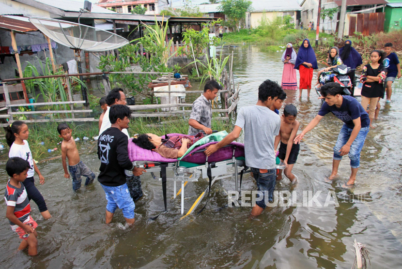 Petugas medis dibantu warga mengevakuasi seorang warga yang sakit saat terjadi banjir di Aceh 