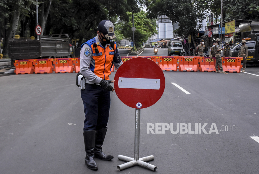 Petugas Dinas Perhubungan Kota Bandung menempatkan rambu lalu lintas saat penutupan ruas jalan di kawasan Dipati Ukur, Kota Bandung, Ahad (6/12/2020).