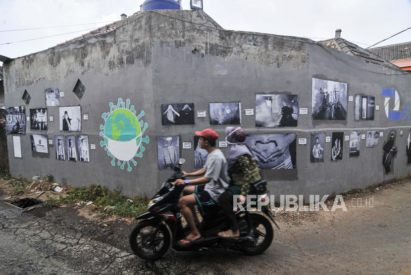 Pengendara motor melintasi foto yang dipamerkan di ruang publik daerah Jati Asih, Bekasi, Jawa Barat, Rabu (8/7/2020). Pameran yang diadakan Komunitas Fotografi Zepret STIKOM Inter Studi menampilkan 23 karya foto untuk mengedukasi warga untuk menjaga kebersihan saat masa pandemi COVID-19. 