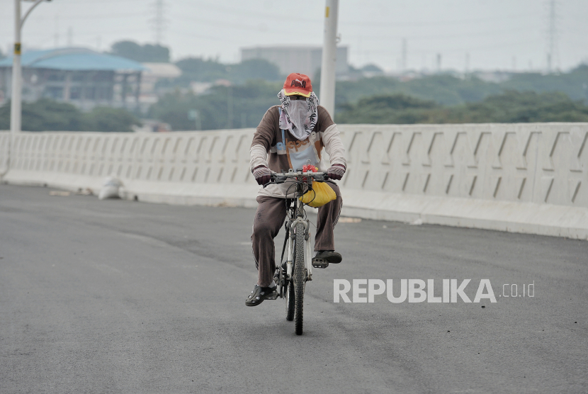 Warga menaiki sepeda melintas di area pembangunanan lintas atas Cakung di Jakarta Timur, Selasa (16/3). 