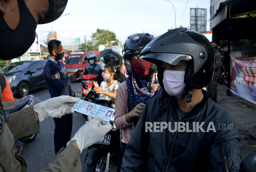 Petugas gabungan memeriksa identitas pengendara motor saat penerapan Pembatasan Sosial Berskala Besar (PSBB) di perbatasan Makassar, Sulawesi Selatan 