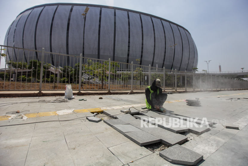 Pekerja memotong paving blok untuk perbaikan trotoar di depan Jakarta International Stadium (JIS). Pj Gubernur DKI Heru Budi sebut pembangunan JPO JIS-Ancol akan selesai dalam 2 pekan.